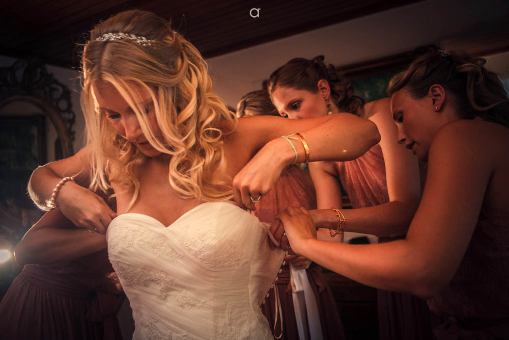 Bridesmaids helping bride to get dressed